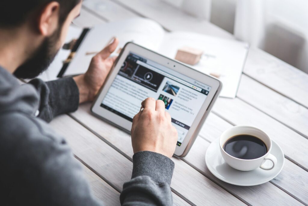 Over the shoulder view of a man viewing online news on a tablet device.